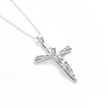 Silver crucifix pendant necklace on a teal fabric background