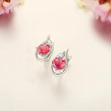 Silver earrings with red gemstones on a soft floral background, featuring the Atta Gems brand.