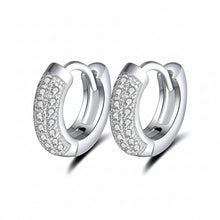 A pair of sterling silver huggie hoop earrings with pavé-set clear stones on one side, shown on a white background with an Orsa Jewels logo and a 925 sterling silver seal.