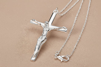 Silver crucifix necklace on a turquoise and beige background