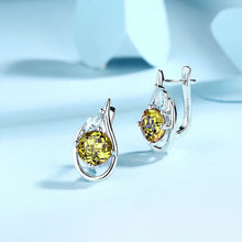 Silver earrings with green gemstones on a light blue background, branded as ATTA GEMS.