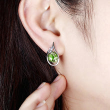 Green gemstone earring being worn, with 'ATTA GEMS' branding.