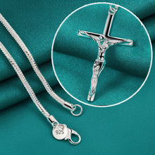Silver necklace with a detailed cross pendant on a teal fabric background, featuring the brand 'Doteeffil'.