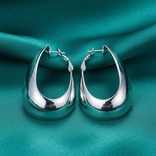 Silver hoop earrings on a teal background with 'Doteffil' branding.
