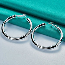 Silver hoop earrings on a teal fabric background with 'Doteffil' branding.