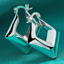 Silver earrings on a teal background with 'Doteffil' branding.