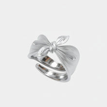 Silver bow-shaped ring on a white background with 'GEEZENCA' branding.