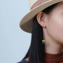 Person wearing a straw hat and earrings with a clear blue sky background