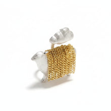 Gold and silver earrings on a brown textured surface with 'GEEZENCA' branding.