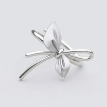Silver bow-shaped earring on a light gray background with 'GEEZENCA' branding.