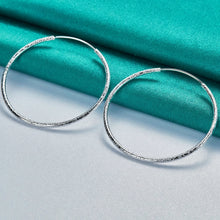 Silver hoop earrings on a teal fabric background with 'Doteffil' branding.