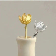 Gold and silver tulip-shaped objects in a beige vase.