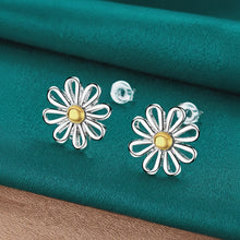 Flower-shaped earrings with gold center on a teal fabric background, brand 'DOFEFFIL' visible.