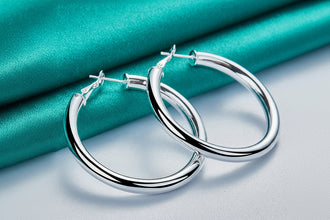 Silver hoop earrings on a turquoise fabric background with 'DOTEEFL' branding.