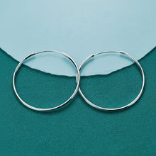 Silver hoop earrings on a teal background with 'DOKEFFIL' branding.