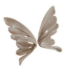 Silver butterfly wing-shaped object with 'Geezenca' branding on a coral-colored background