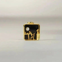 Gold and black pendant with a pearl on a light gray background, featuring the brand 'GEEZENCA'.