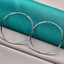 Silver hoop earrings on a teal and gray fabric background with 'Doteffil' branding.