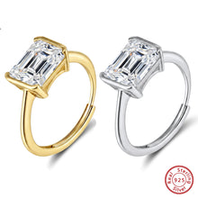 Two hoop-style earrings with large rectangular clear gemstones are shown on a white background. One earring has a yellow gold setting and the other has a silver setting.