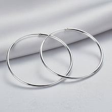 Pair of silver hoop earrings on a light blue fabric background with 'Doteefil' branding.