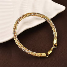 Gold braided bracelet on a brown surface with 'GEEZENCA' branding.