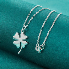 Silver necklace with clover pendant on a teal fabric background