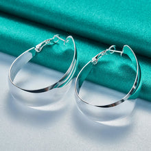 Silver hoop earrings on a turquoise fabric background with 'Doteefil' branding.