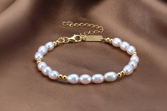 Pearl bracelet with gold accents on a brown fabric background