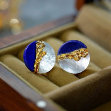 Jewelry set with blue and gold design on a beige cushion, brand 'GEEZENCA' visible.