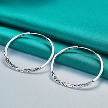 Silver hoop earrings on a teal fabric background with 'DOTEEFFIL' branding.