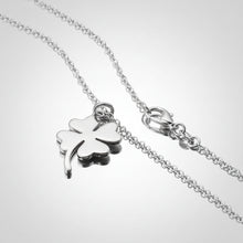 Silver chain necklace with a four-leaf clover pendant on a teal and gray background.