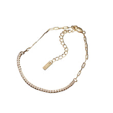 Gold bracelet with a tag on a dark surface, branded 'Orsa Jewels'.
