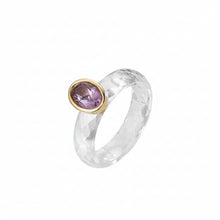 Ring with purple gemstone and gold setting on a white background