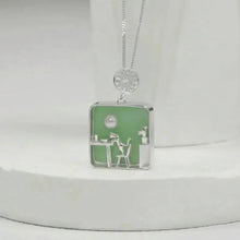 Necklace with a pendant featuring a design of a person sitting at a desk on a white surface, branded 'GEEZENCA'.