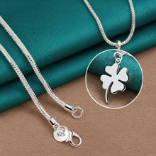 Silver four-leaf clover pendant with chain on a teal fabric background, featuring the Doteeffil brand.