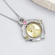 Gold and silver pendant with gemstones on a white background, featuring the brand 'Geezenca'.