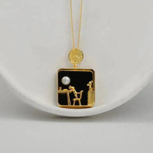 Gold necklace with a pendant featuring a black square design on a white background