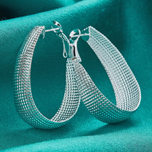 Silver hoop earrings on a teal fabric background with 'DOVEFIL' branding.