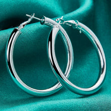 Silver hoop earrings on a teal fabric background with 'DOFEFFIL' branding.