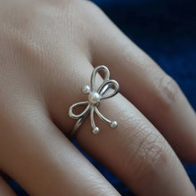 Silver bow-shaped ring on a finger with 'GEEZENCA' branding.