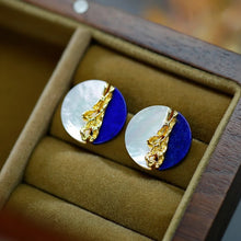 Pair of earrings with gold and blue design in a box, brand 'GEEZENCA' visible