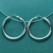 Silver hoop earrings on a teal background with Doteeffil branding.