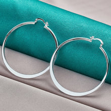 Silver hoop earrings on a teal and gray fabric background with 'Doteefil' branding.