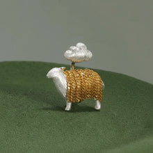 Gold and silver sheep figurine on a green surface with 'GEEZENCA' branding.
