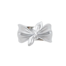 Silver bow-shaped ring on a white background with 'Geezenca' branding.