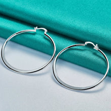 Silver hoop earrings on a teal fabric background with 'Doteffil' branding.