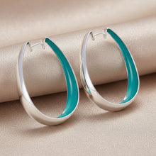 Silver hoop earrings on a teal fabric background with 'DOFEFFIL' branding.