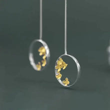 Earrings with gold floral designs on a dark background