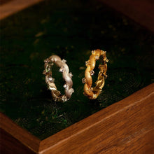 Two gold rings on a dark green surface with 'GEEZENCA' branding.