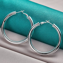 Silver hoop earrings on a teal and gray fabric background with 'Doteefil' branding.
